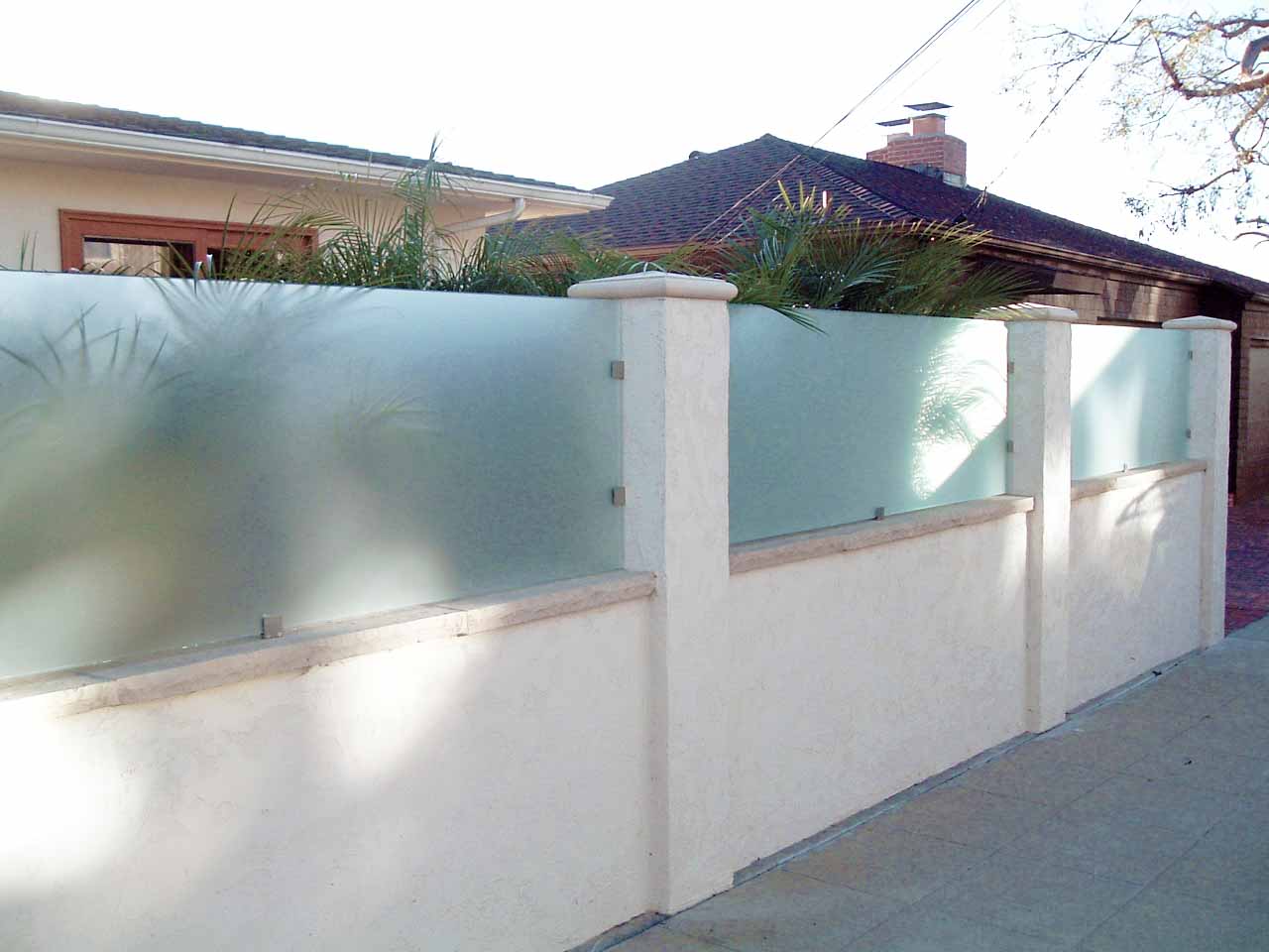 Outdoor glass railings over a concrete wall.