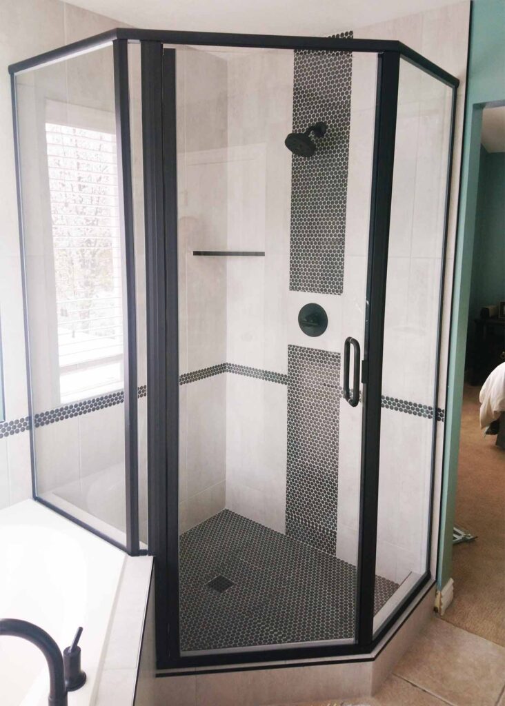 Corner shower enclosed with black framed glass.