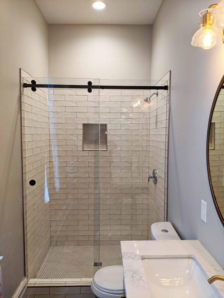 Frameless glass shower doors in a farmhouse bathroom.