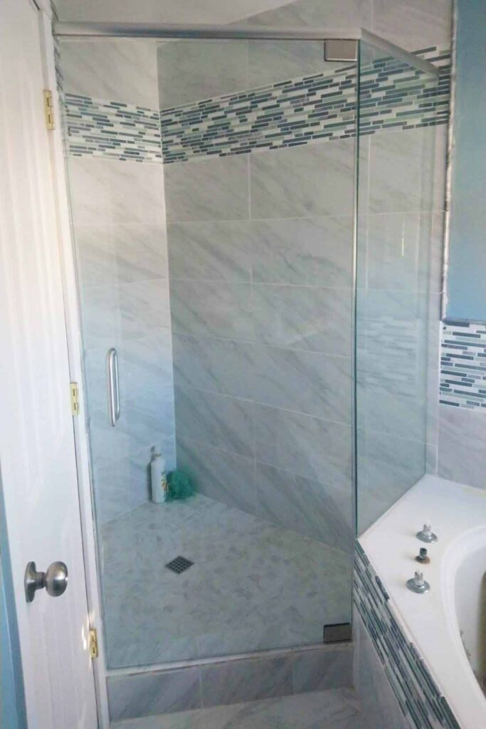 White and blue bathroom with frameless shower door & enclosure.