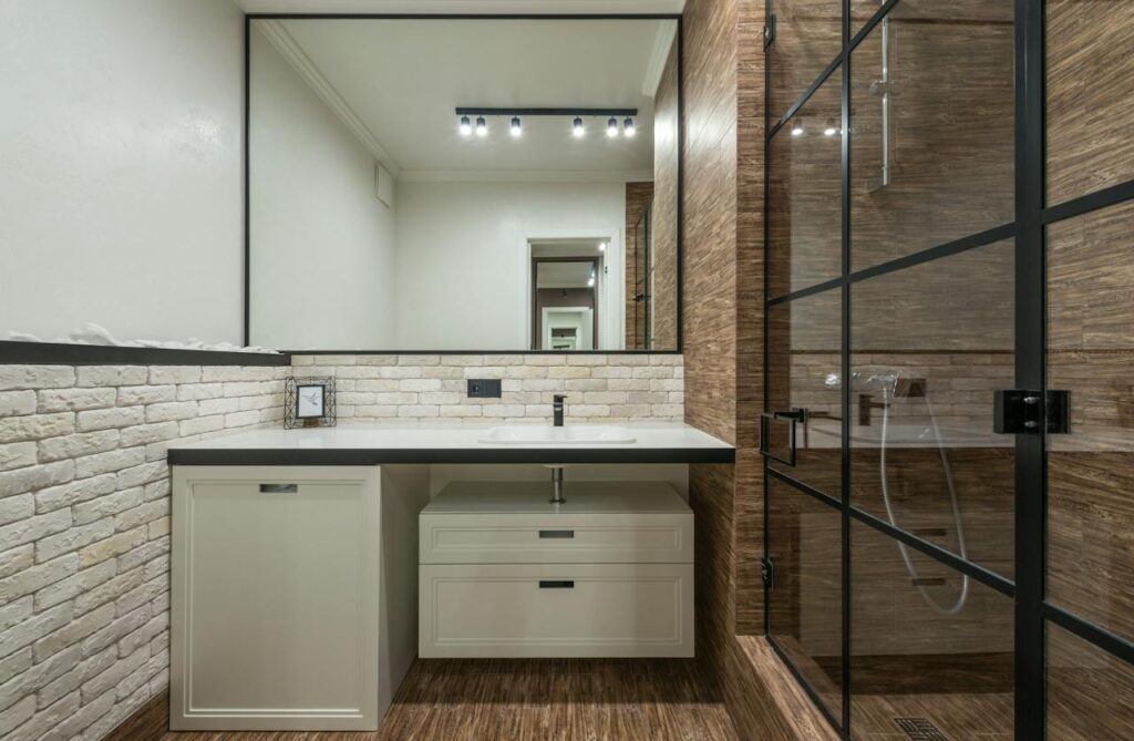 Framed glass shower divider, modern bathroom a mix of bricks and long tiles.