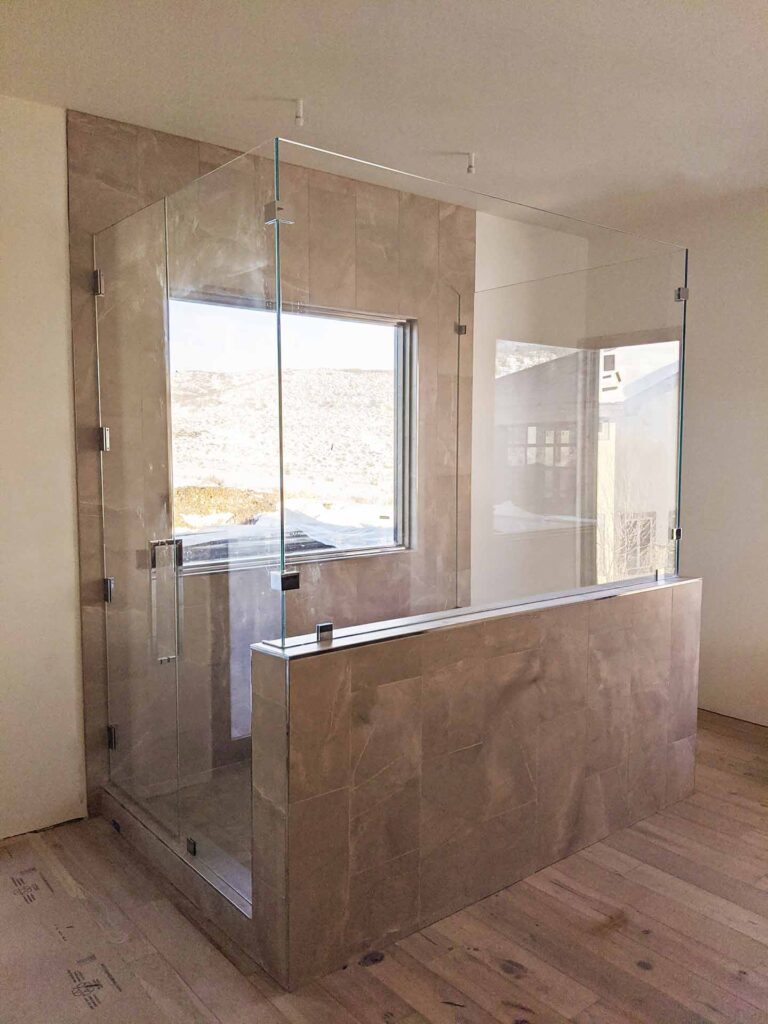 Unique centered shower with half wall and custom glass enclosure.